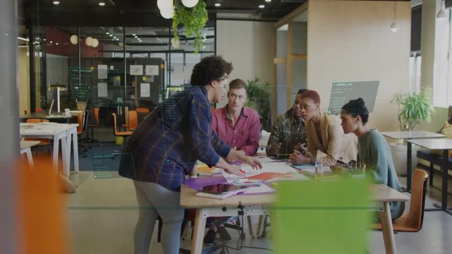 Presenter moving to table, handing red sheet and arranging mockups while team reviewing for pitch