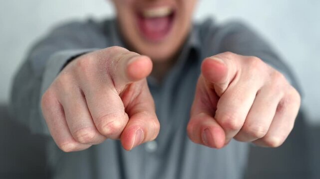 Close-up of a young male pointing forward and smiling in a teasing way, suggesting provocation or social interaction with humorous tone.
