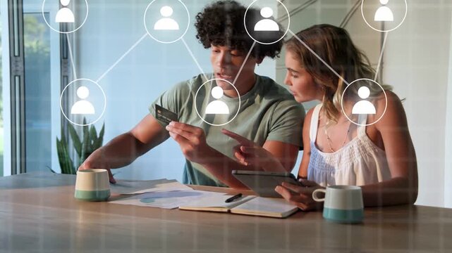 Man holding credit card, woman tapping tablet paying bills while network map growing around tablet