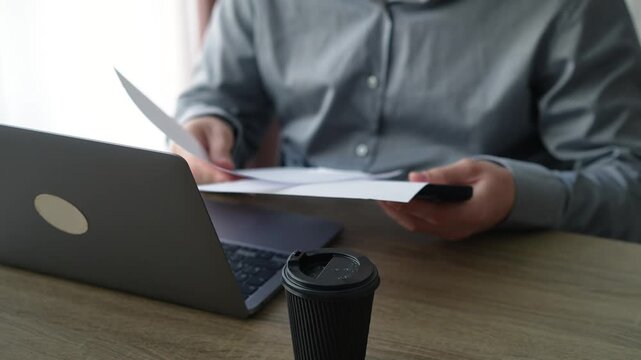 Businessman sitting in his office carefully analyzing printed documents and reviewing important paperwork on his desk. Concept of business analysis and decision making.