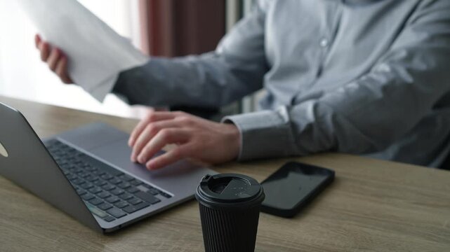 Businessman sitting in his office carefully analyzing printed documents and reviewing important paperwork on his desk. Concept of business analysis and decision making.