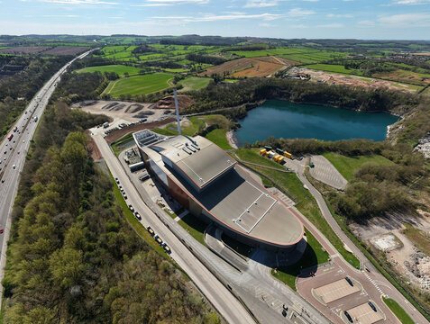 Aerial view of the Encyclis Newhurst ERF industrial facility next to a quarry lake and green fields in Shepshed, England, United Kingdom.