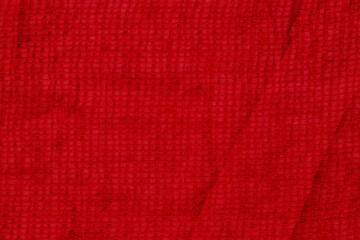 Fototapeta premium Bright red fabric with a textured surface on display in a bright light setting, possibly indoors or outdoors
