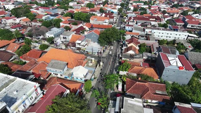 Aerial view of a densely populated residential area with traditional red roofs in a Southeast Asian city.