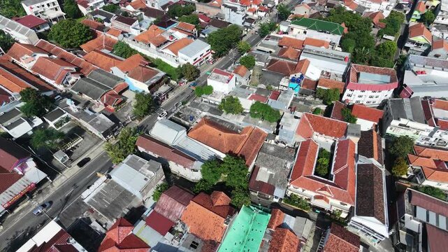Aerial view of a dense residential neighborhood with red tiled roofs in a Southeast Asian city.