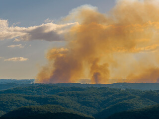 Fototapeta premium Thick orange smoke across the ridgeline caused by hazard reduction burning in the late afternoon as the sun was setting in the Blue Mountains in New South Wales, Australia