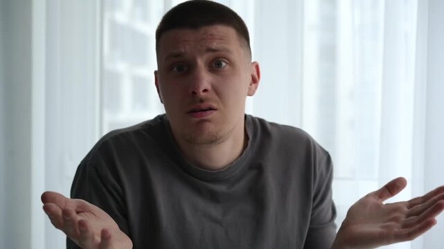 Man expressing confusion and disbelief, raising his hands in a questioning gesture, showing he does not understand the situation. Concept of misunderstanding and uncertainty.