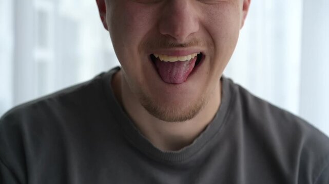 Close-up of a young man licking his lips, showing slightly dry skin, suggesting dehydration or need for lip care. Concept of natural body response and personal care.