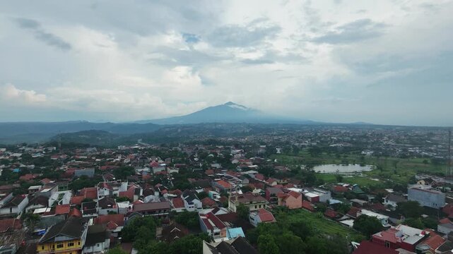 Aerial view of urban city landscape with mountain background and cloudy sky.