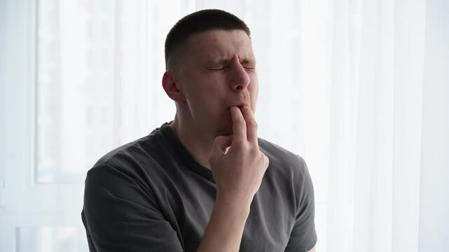 Young male whistling loudly using fingers in his mouth in a bright room, trying to get attention. Concept of call signal, alert, and human communication.