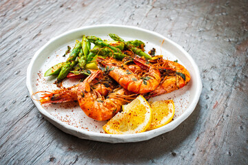 Grilled spicy white tiger prawns in shell with green asparagus as tapas served as close-up in a...
