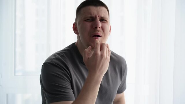 Young male whistling loudly using fingers in his mouth in a bright room, trying to get attention. Concept of call signal, alert, and human communication.