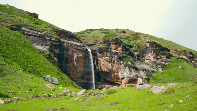 4K Wide angle shot of Paralam waterfall flowing from a cliff during the summer season as seen from Sural Bhatori in Pangi Valley of Chamba district, Himachal Pradesh, India. Natural background.
