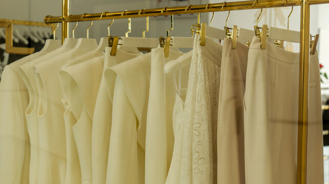 Elegant cream and beige women's clothing collection displayed on a gold rack
