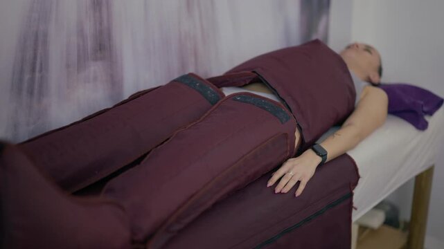 A woman is undergoing a pressotherapy procedure at a beauty salon. This wellness treatment involves specialized equipment to enhance circulation and lymphatic drainage.