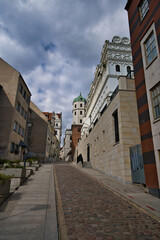 Fototapeta premium Historic European Cobblestone Street Lined With Ornate Buildings And Tower Under Dramatic Sky - Szczecin - Castle of the Pomeranian Dukes.