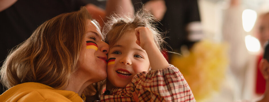 Excited football fans, supporting German national team in live soccer match at stadium.