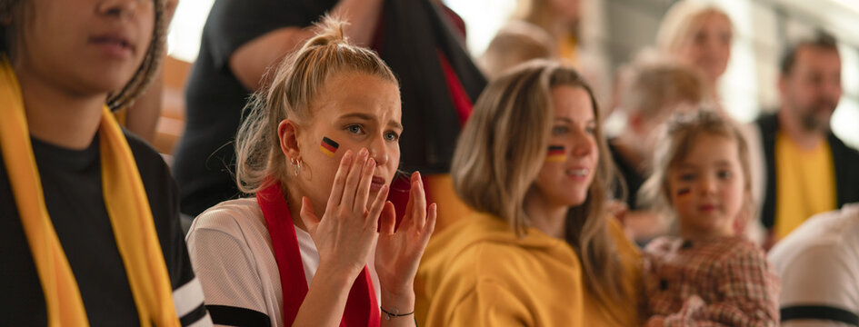 Worried football fans supproting German national team in live soccer match at stadium.