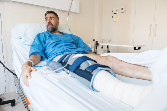 Male patient recovering from knee surgery in hospital bed