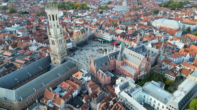 Aerial drone footage of the historic Markt square in Bruges, Belgium. Featuring the medieval Belfry tower (Belfort), colorful guild houses, and the Provincial Court building . Version 6.