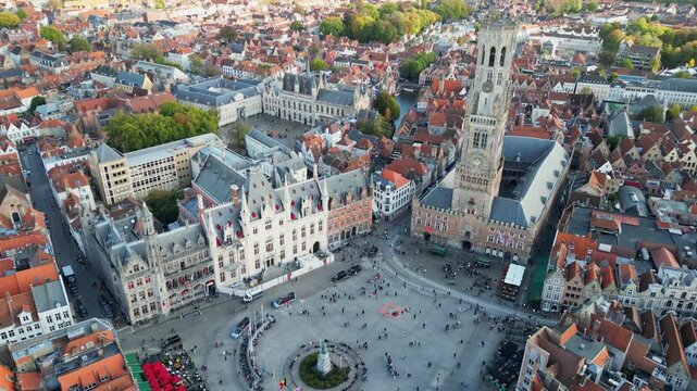 Aerial drone footage of the historic Markt square in Bruges, Belgium. Featuring the medieval Belfry tower (Belfort), colorful guild houses, and the Provincial Court building . Version 3.
