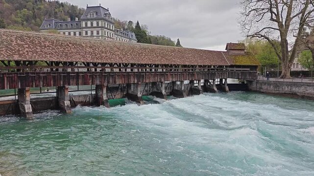 Historic Covered Wooden Bridge Over Turquoise Aare River in Thun Switzerland
