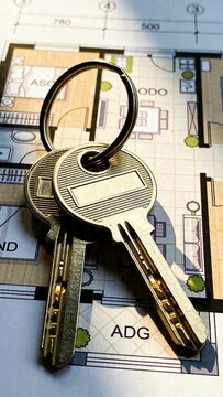 Close-up of house keys on an architectural floor plan, symbolizing homeownership and real estate investment.
