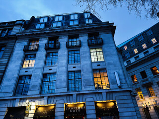 Naklejka premium Traditional pub Traitors Gate on a historic stone building facade in London, UK at blue hour with illuminated windows and evening street atmosphere