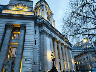Naklejka premium Historic neoclassical 10 Trinity Square courthouse with illuminated columns at dusk in London, UK showcasing grand civic architecture and stone facade. Four Seasons Hotel London at Ten Trinity Square.