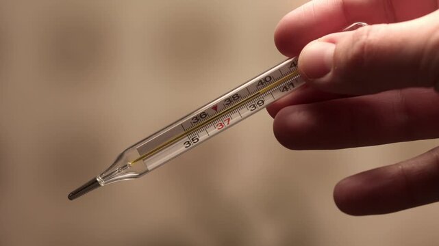 Woman holds mercury thermometer in her hands to measure body temperature, disease, Doctor or nurse, sick patient. Fever from Covid-19 virus. Deadly diagnosis. Coronavirus pandemic, flu epidemic