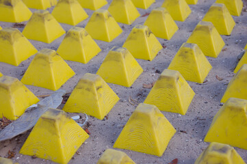 Close-up diagonal shot of bright yellow safety studs arranged in neat rows on concrete tactile...