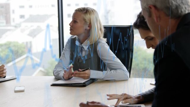 Blonde woman leaning and speaking, causing animated financial chart overlaying tablet for review