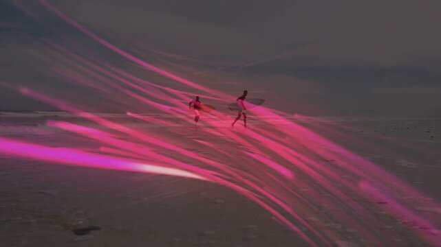 Two surfers running to surf with boards magenta streaks crossing over surfers reflecting on sand
