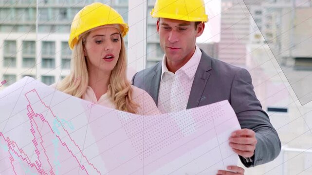 Pair putting on yellow hard hats for site review, gesturing over plan, graphs overlaying plan, hats