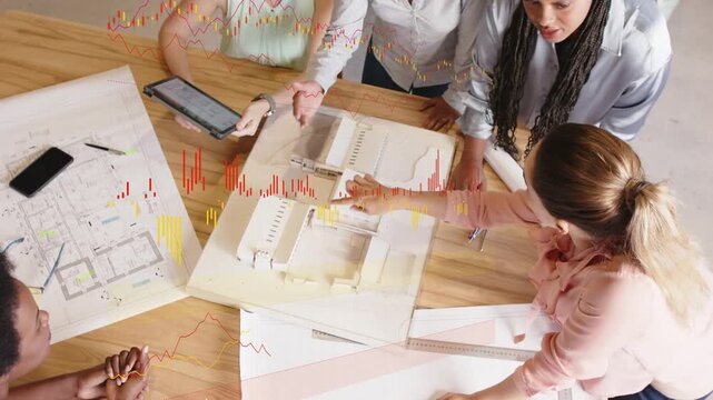 Five women leaning over design model, finalizing plans while tablet tilt bringing up charts
