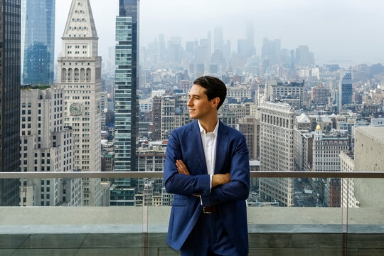 Well dressed young man standing on rooftop with New York City skyline