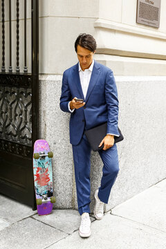 Stylish young man checking smartphone on city sidewalk in New York City