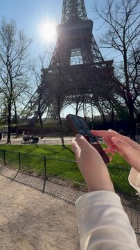 Image of person holding phone with Eiffel Tower background during daytime