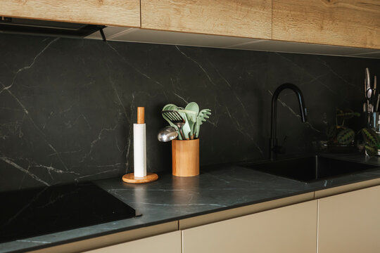 Modern kitchen countertop with utensils and paper holder in natural style on dark stone background showing home interior concept