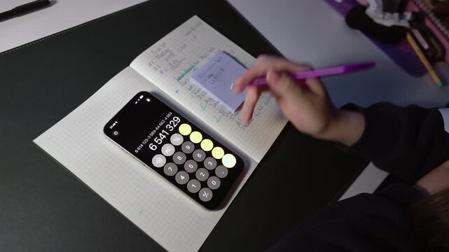 Woman calculating numbers on her smartphone and making notes. Money for rent expenses and income