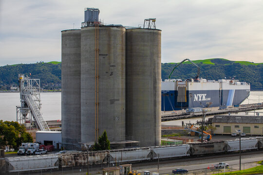 Industrial waterfront silos and cargo vessel operations along the Martinez shoreline