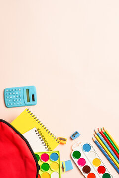 School backpack with stationery on colored background.