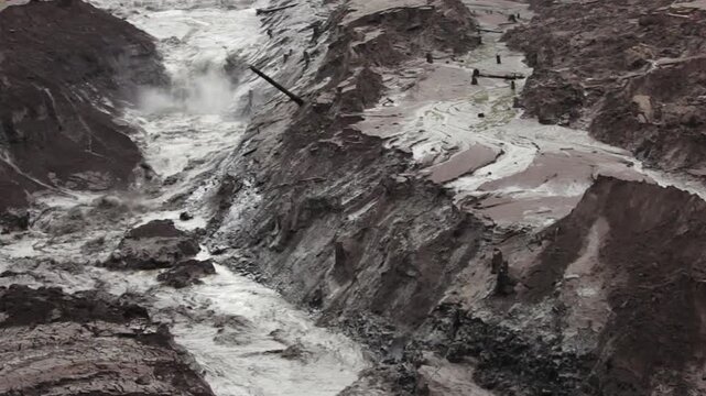 Destructive mudflow torrent rushing through a gorge, causing severe soil erosion
