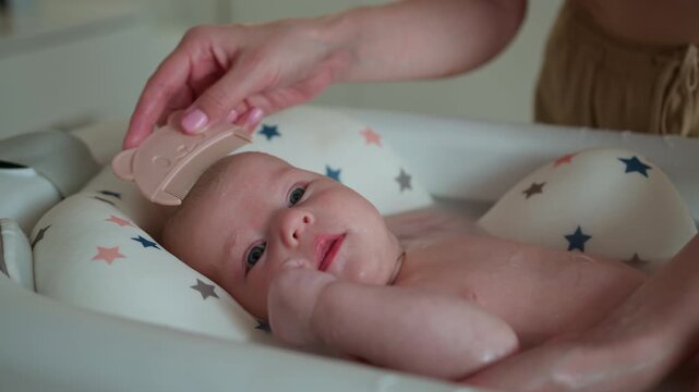 Parent gently combs newborn baby hair during bath time with cute bear shaped comb promoting hygiene comfort care and bonding. Infant child family love parenthood cozy home adorable childhood innocence