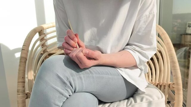 Home manicure process shows cuticle pushing with wooden stick on nails. Female performs selfcare routine shaping natural fingernails. Beauty concept reflects hygiene and neat appearance