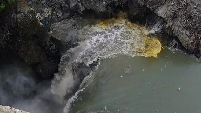 Large rock explosion causing a landslide of debris and dust into a lake in a stone quarry