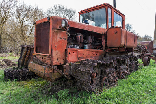 Vintage rusty crawler tractor abandoned in grass, old agricultural machinery concept for farming, rural heritage, industry, restoration, mechanical decay.
