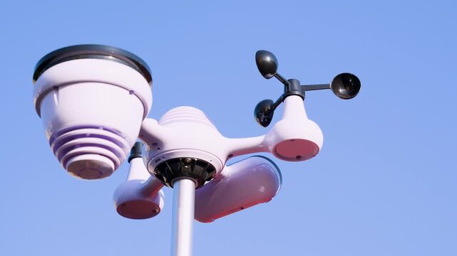 Weather station with wind cups and sensors installed on pole under clear sky. Urban meteorological observation equipment.