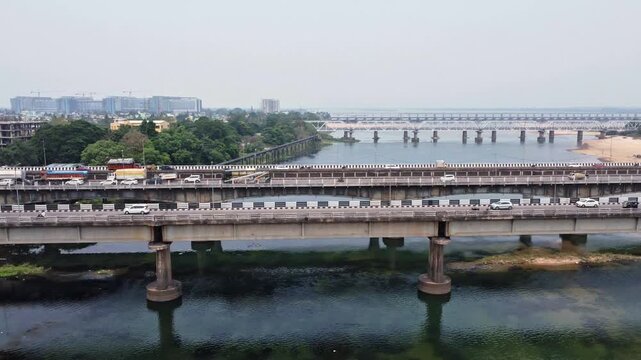 Heavy Indian Vehicle Traffic Crossing Bridge Over River in Indian Urban City. Indian City Transport Traffic Flow on Bridge Across River Landscape. Indian Truck, Indian Car and Indian bus Traffic.