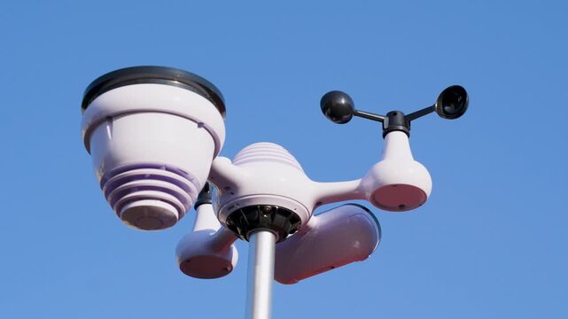 Weather station with wind cups and sensors installed on pole under clear sky. Urban meteorological observation equipment.